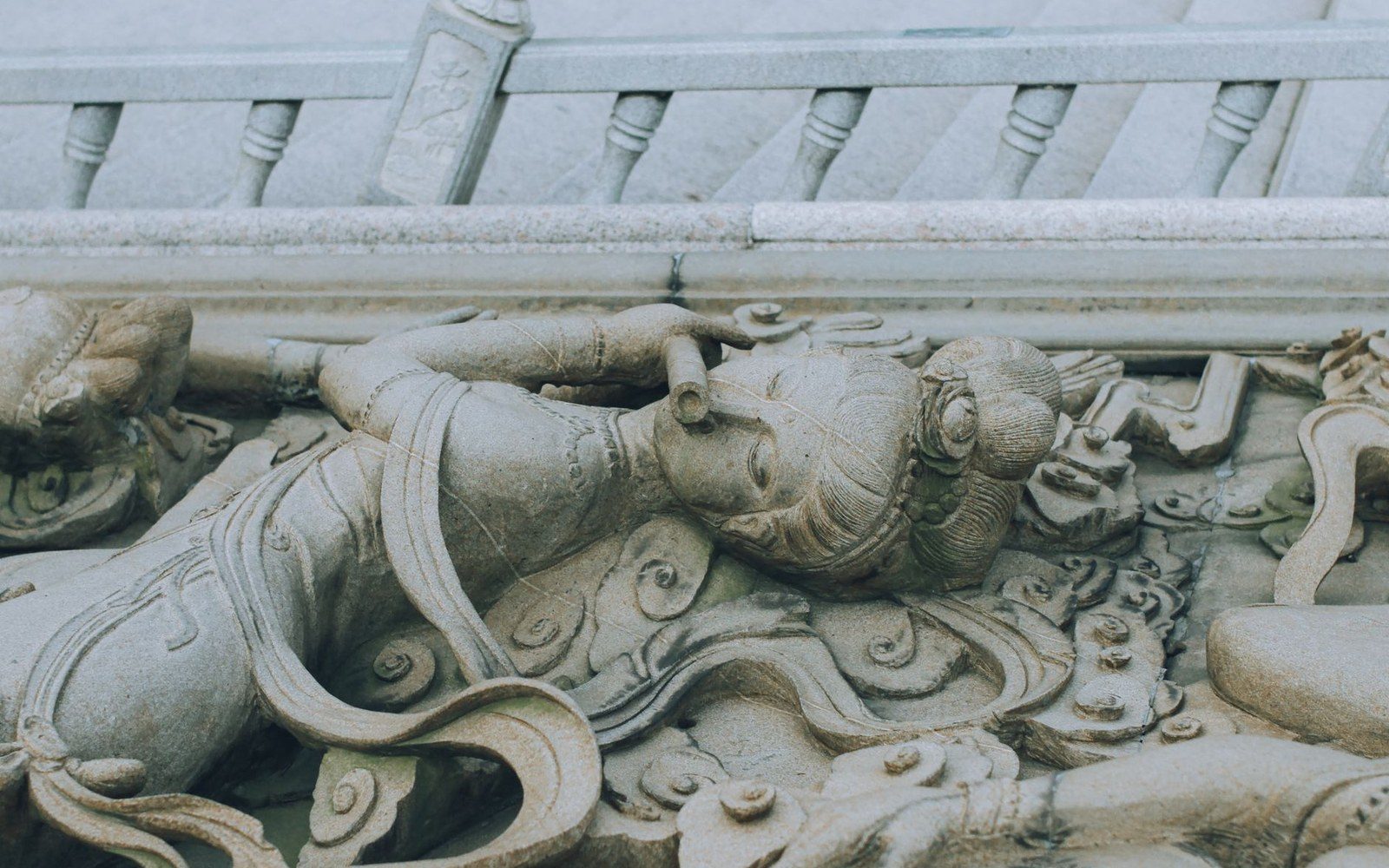 A close-up of a carved woodblock showing a Marseille tarot figure in relief, the worn edges of the cut lines visible under raking light