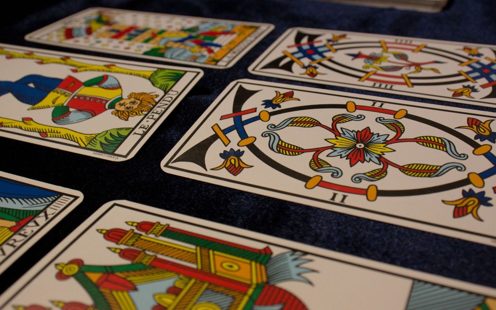 Tarot cards including The Hanged Man laid out on a dark blue cloth