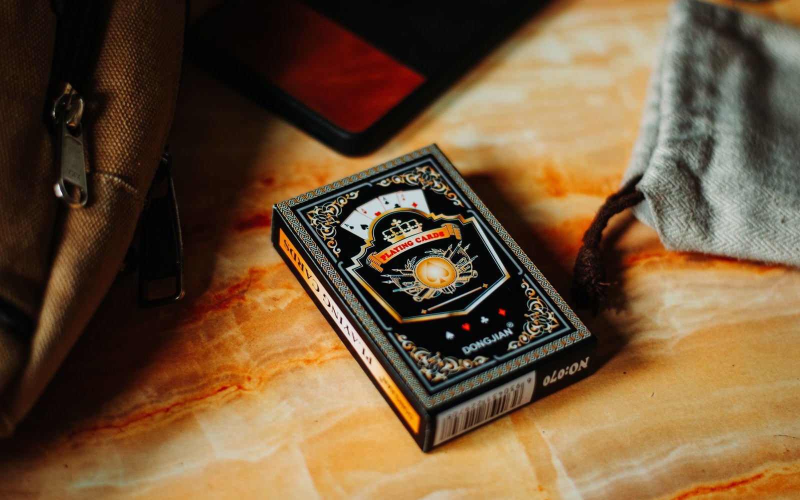 A tarot deck tuck box open, the flap at an angle showing the board thickness and the inner tray, photographed on a flat surface